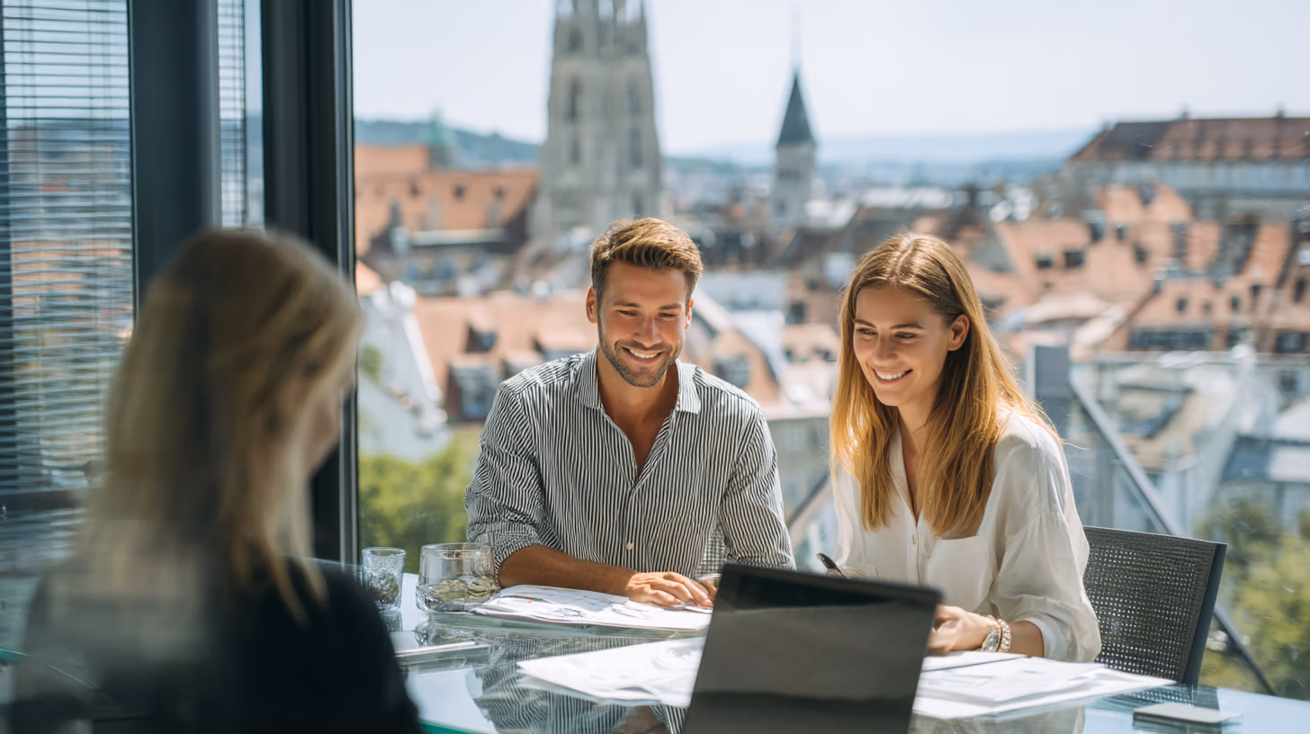 Zwei junge Menschen bei einem Marketing-Meeting mit Blick auf die Altstadt, lächelnd am Glastisch
